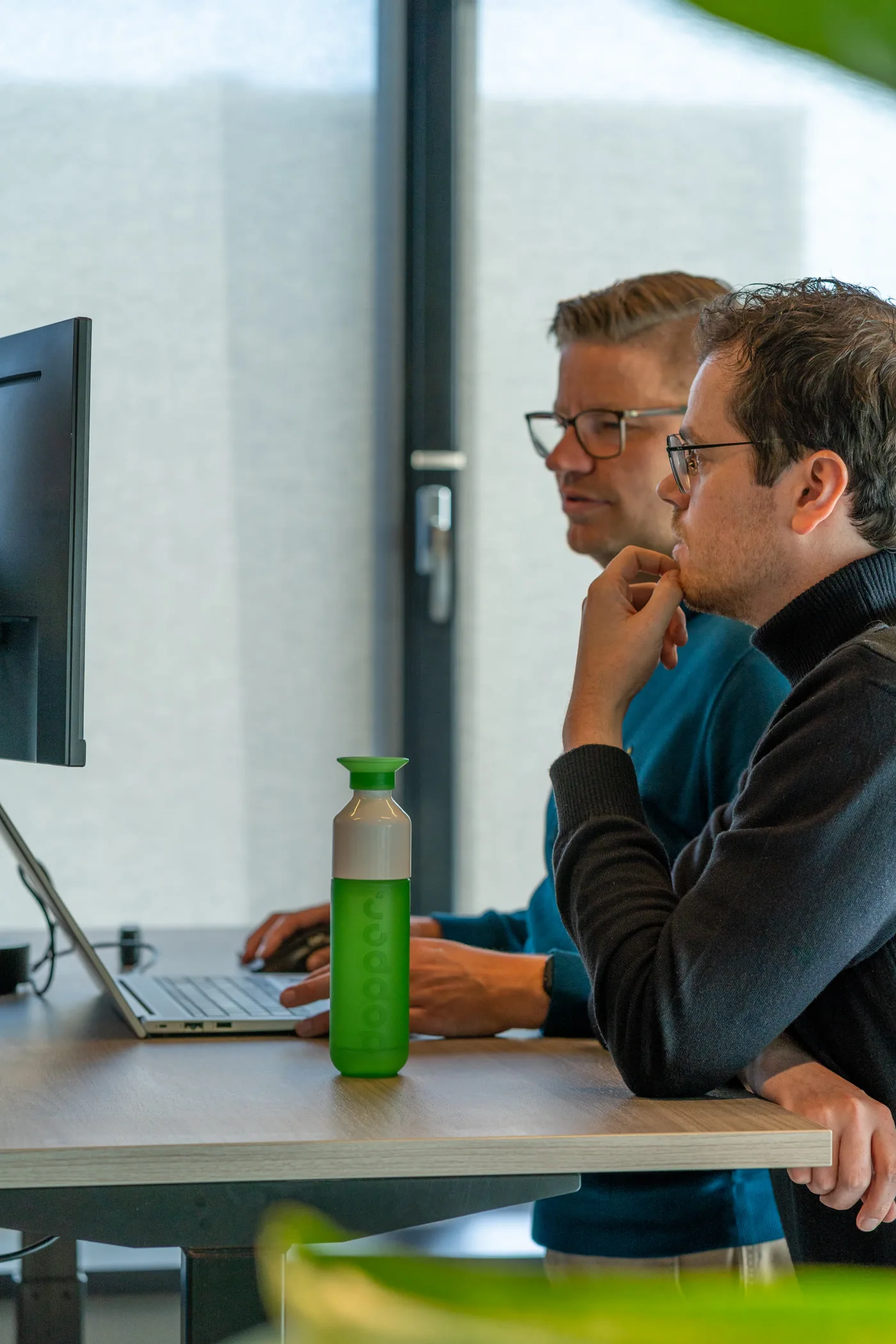Twee Flinker collega's werken samen achter een laptop en monitor